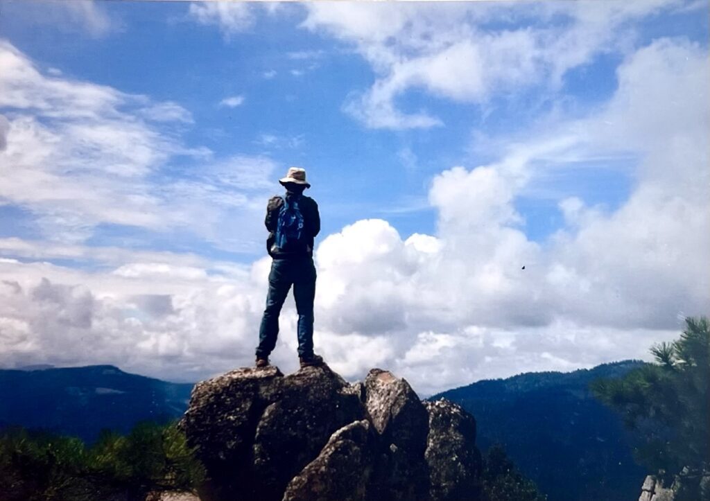 Hiker on a mountaintop with a blue sky.
